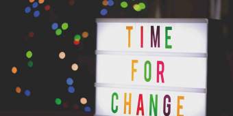 backlit sign with colored letters that reads time for change